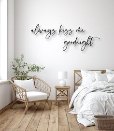 a bedroom with white walls and wood flooring has a large metal sign that says always kiss me goodnight