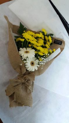 a bouquet of yellow and white flowers wrapped in burlock