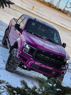 a purple truck driving down a snow covered road