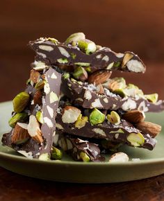 chocolate barkle with pistachios and almonds on a green plate sitting on a wooden table