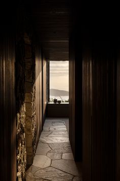 an empty hallway with stone walls leading to the ocean