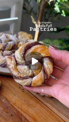 a person holding a pastry in front of some other pastries on a cutting board