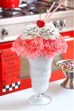 a vase filled with pink carnations and sprinkles on top of a counter