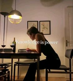 a woman sitting at a table writing on a piece of paper