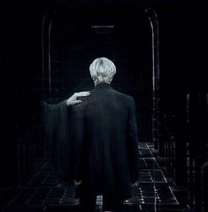 a man with white hair is standing in a dark room and holding his back to the camera