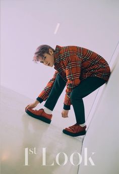 a young boy is leaning on the edge of a wall and looking down at his shoes