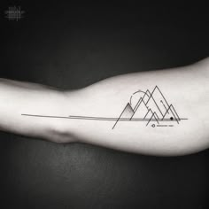 a black and white photo of a tattoo on the arm with mountains in the background