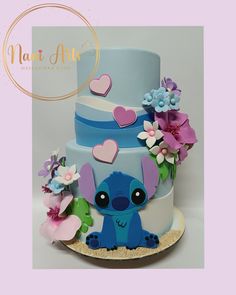 a blue and purple cake with a little stitcher on the top is surrounded by flowers