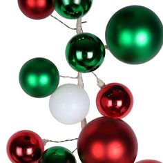 green and red ornaments are hanging on a white string