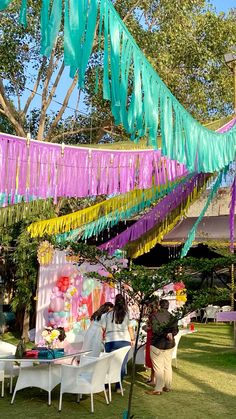 people are sitting at tables under colorful streamers