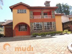 an orange house with white balconies on the front and second story, surrounded by brick pavers