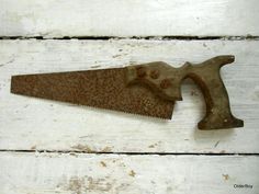 an old rusted metal object with a hammer stuck in it's side on a white wooden surface