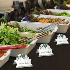 salads are lined up in white bowls on a table with name tags attached to them