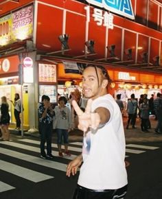 a man standing in front of a store pointing at the camera with his finger up