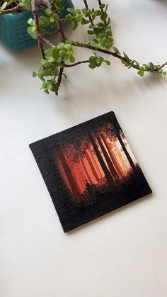 a plant is sitting on a table next to a small card with an image of trees