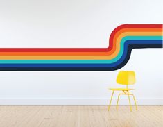 a chair sitting next to a wall with a rainbow painted on it