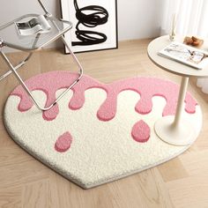 a heart shaped rug with pink and white designs on the floor next to a table