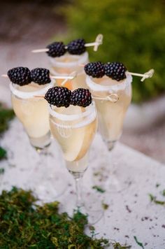 three glasses filled with champagne and topped with blackberries