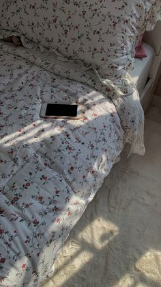 a white bed with floral sheets and pillows