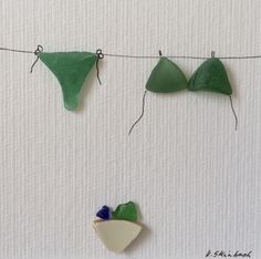 three pieces of green and white glass hanging on a line with string attached to it