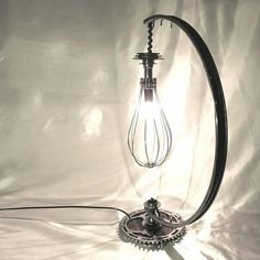 a lamp that is on top of a white sheet with a light bulb attached to it