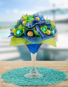 a bouquet of chocolates in a wine glass on a table with a blue doily