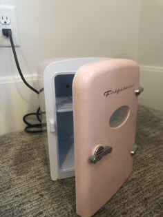 an old fashioned pink refrigerator sitting on the floor next to a plugged in outlet