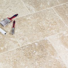 two tools are laying on the floor next to each other, including a brush and squirt