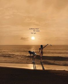 two women standing on stilts in front of the ocean with a sunset behind them