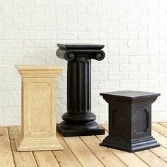 three black and white pedestals sitting on top of a wooden floor