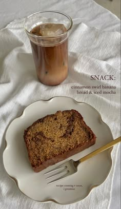 a piece of bread on a plate next to a glass of iced tea and a fork