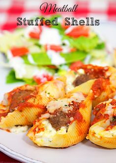 stuffed shells on a plate with salad and dressing in the background text reads, meatball stuffed shells