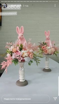 two vases filled with flowers and bunny ears on top of a white tablecloth