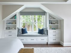 a bed sitting under a window in a bedroom next to a book shelf filled with books