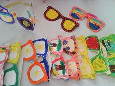 several pairs of colorful sunglasses are laid out on a white surface with other items in the background