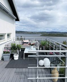 a balcony with potted plants on it and a couch in the foreground, next to a body of water