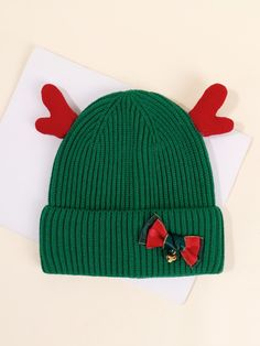 a green knit hat with red antlers on it and a white envelope next to it