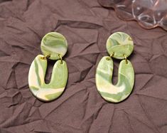 two green and white earrings sitting on top of a bed