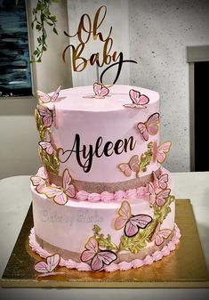 a three tiered cake with pink butterflies on it and the words, oh baby ayen