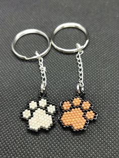 two key chains with an orange and white dog paw bead pattern on each one