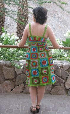 a woman in a colorful dress is looking over a stone wall