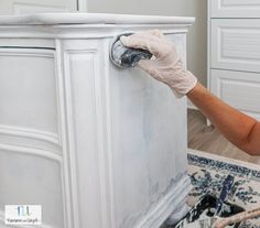 a woman in white gloves painting a cabinet