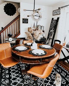 a dinning room table with chairs and plates on it in front of the stairs