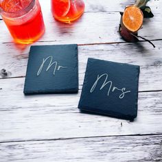 two slate coasters with mr and mrs written on them next to some orange slices