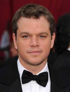 a man in a tuxedo and bow tie at an oscars red carpet