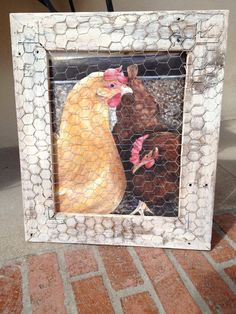 a chicken and hen painting in a frame on the ground