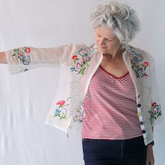 an older woman pointing at something with her right hand and wearing a red striped shirt