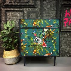 a painted dresser next to a potted plant