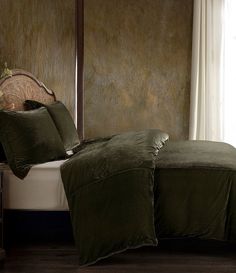 a bed with green sheets and pillows in a room