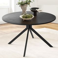 a black table with two white plates on it and a potted plant in the middle